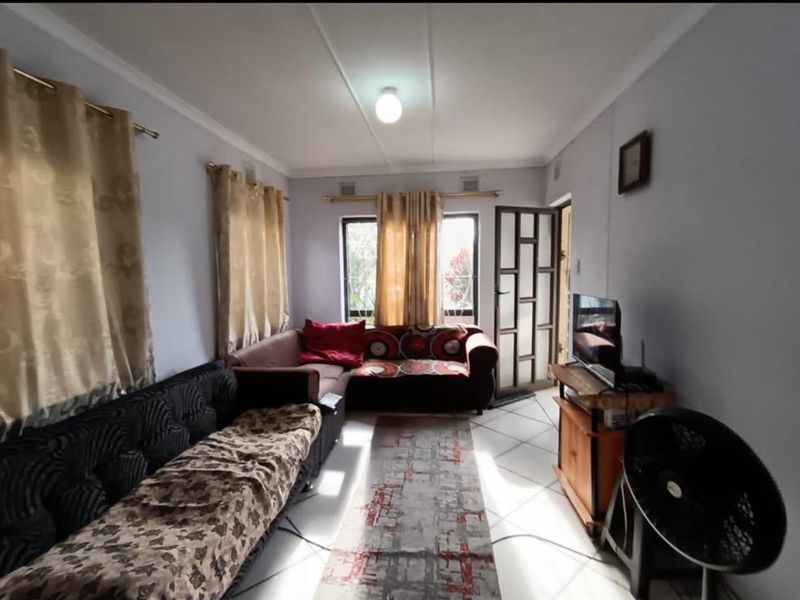 A functional living room featuring tiled flooring, cornicing, and a glazed entrance door, providing a bright and accessible living space.