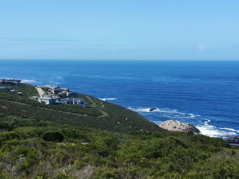 A scenic coastal view overlooking the ocean and surrounding hillside landscape, showcasing the natural beauty and prime location of the residential area.