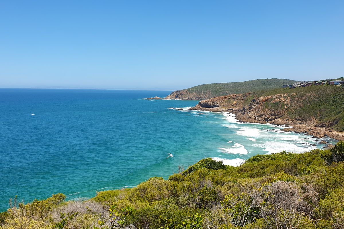 A scenic coastal view overlooking the ocean, rocky cliffs, and natural vegetation, showcasing the property's prime location.