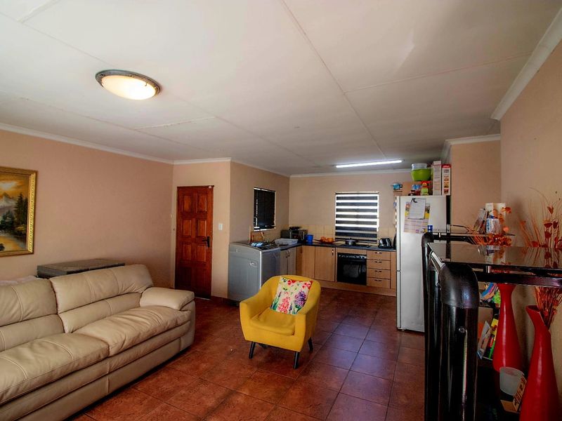 Open-plan living area featuring tiled flooring and a functional kitchen with built-in cabinetry, oven, and hob.