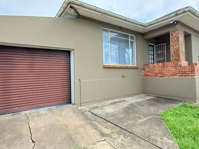 Front elevation of the house featuring a single roller garage door, brick detailing, and a concrete driveway with visible surface cracking.