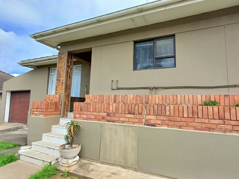 Front elevation of the house featuring a brick retaining wall, concrete entrance steps, and a single garage with a roller door.