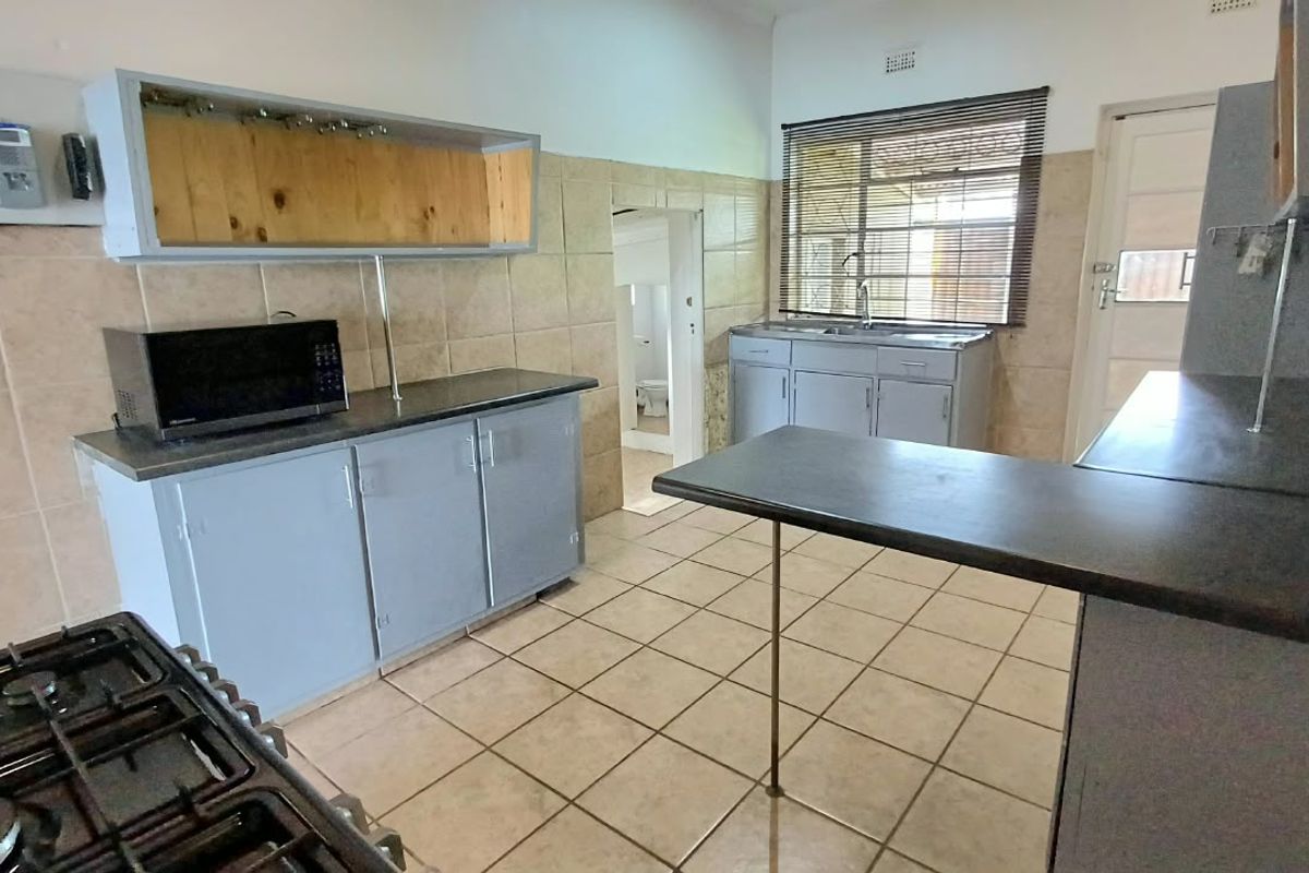 Functional kitchen featuring tiled flooring, built-in cabinetry, a breakfast bar, and a gas hob, offering potential for modern updates.