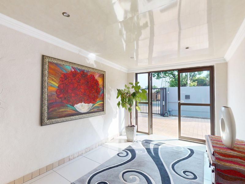 Bright entrance hall featuring glossy ceiling finish, recessed lighting, and large sliding glass doors providing direct access to the exterior paved area.