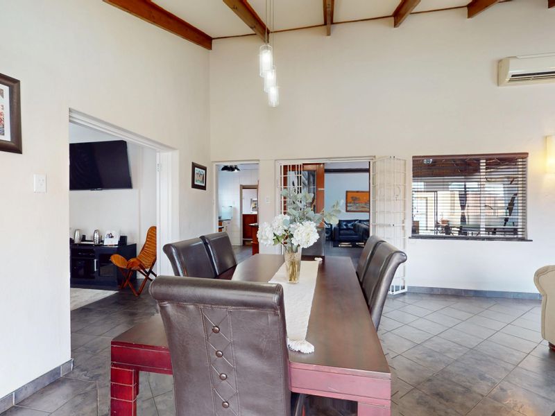Spacious dining area featuring high ceilings with exposed timber beams, tiled flooring, and an integrated air conditioning unit.