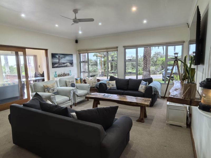 Spacious living room featuring large windows, recessed downlights, a ceiling fan, and sliding glass doors leading to an outdoor area.