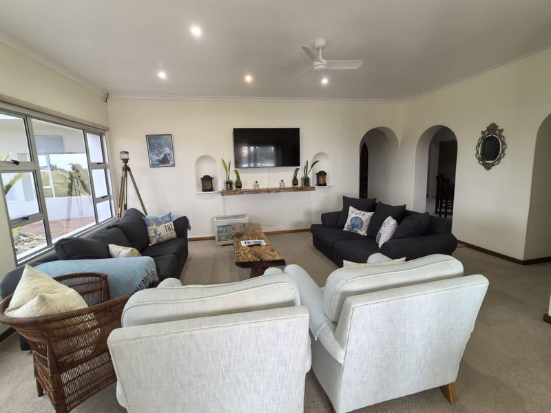 Spacious living room featuring arched doorways, built-in wall niches, large windows providing natural light, and neutral carpeting throughout.