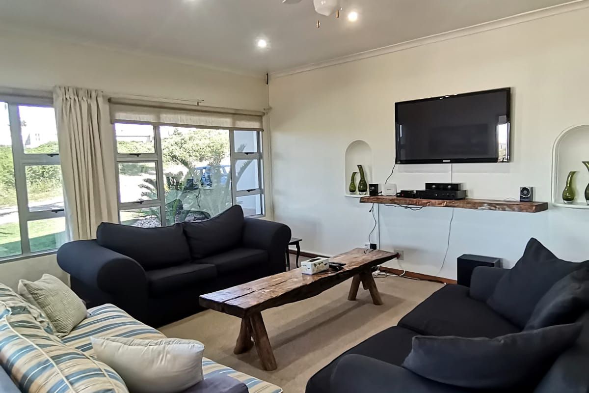 A comfortable living room featuring recessed lighting, a ceiling fan, and built-in wall niches, with large windows providing natural light.