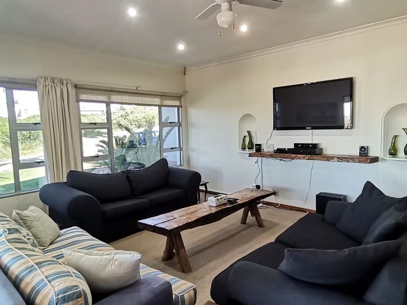 A comfortable living room featuring recessed lighting, a ceiling fan, and built-in wall niches, with large windows providing natural light.