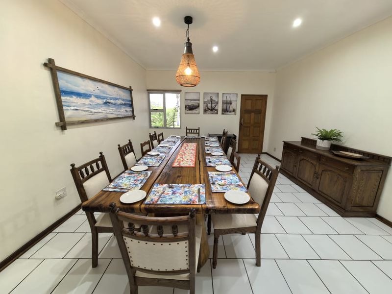A spacious dining room featuring tiled flooring, recessed downlighting, and a central pendant light, providing a functional area for family meals and entertaining.
