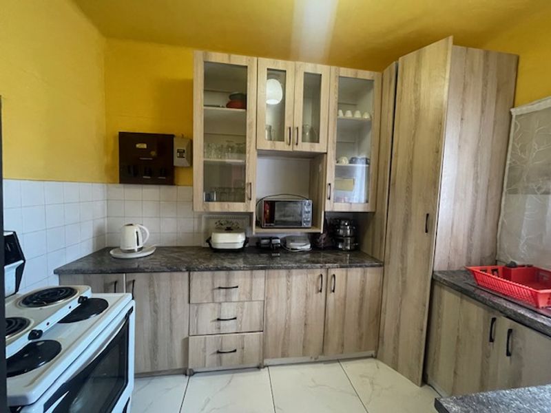 A functional kitchen featuring light wood-look laminate cabinetry, tiled backsplash, and ample storage space, providing a practical layout for daily meal preparation.