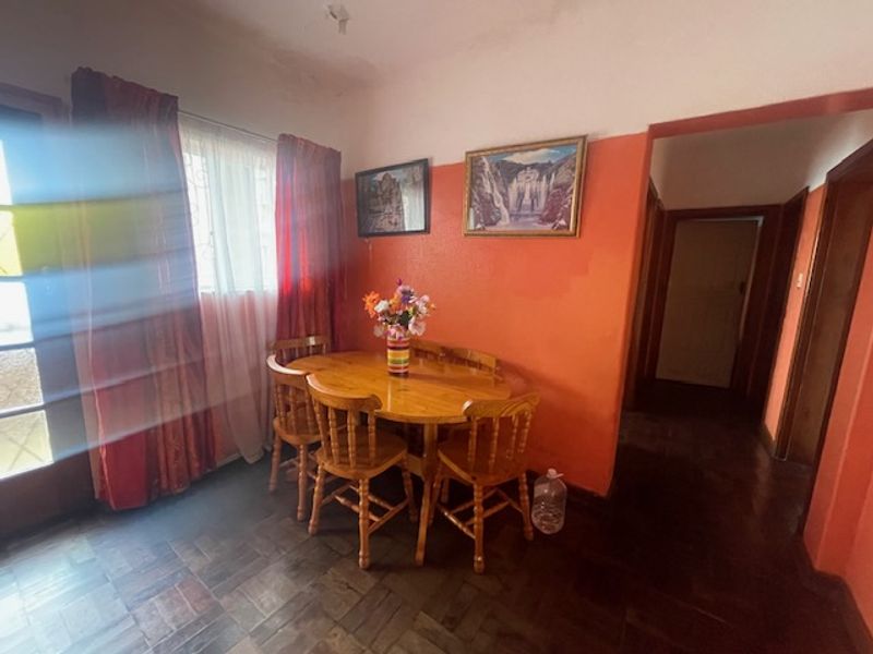 Dining area featuring parquet flooring and access to a hallway, with potential for modernization through updated paint and finishes.