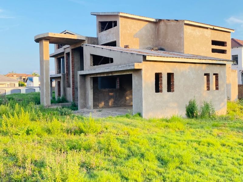 An unfinished double-story residential property structure in the early stages of construction, featuring exposed masonry and a concrete frame on a large plot.