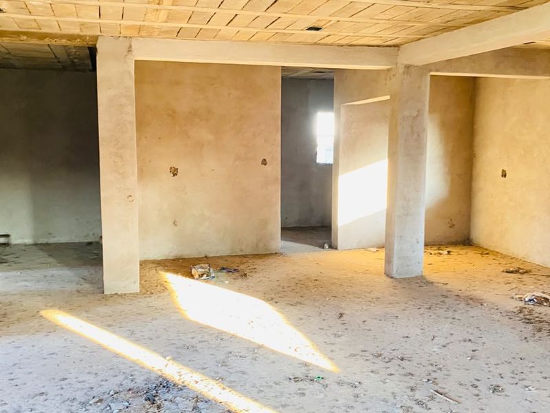 An unfinished open-plan interior space featuring exposed concrete columns and ceiling, currently in a shell condition awaiting final finishes and flooring.