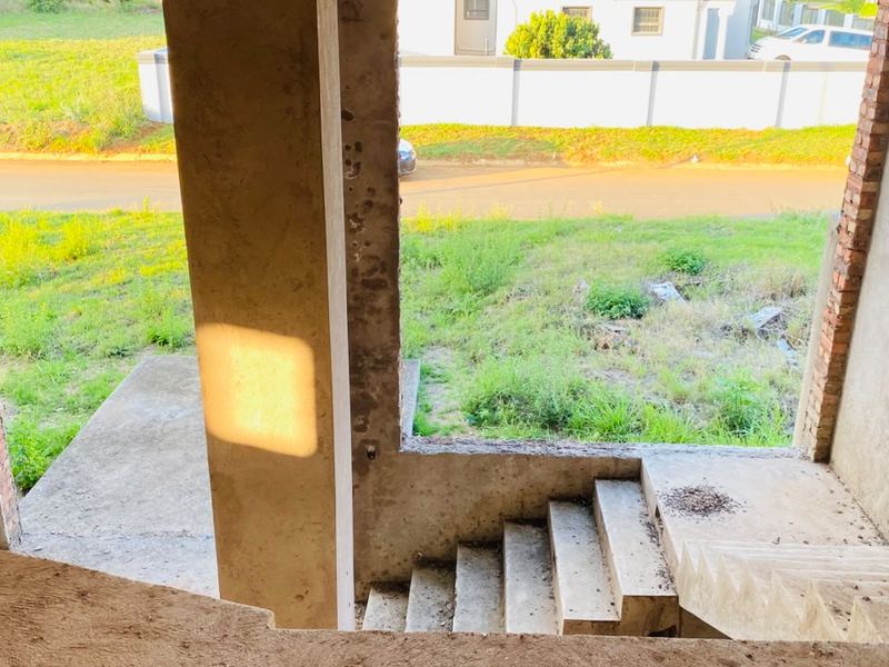 An unfinished interior entry area featuring raw concrete stairs and structural columns, currently in a shell state awaiting completion and final finishes.