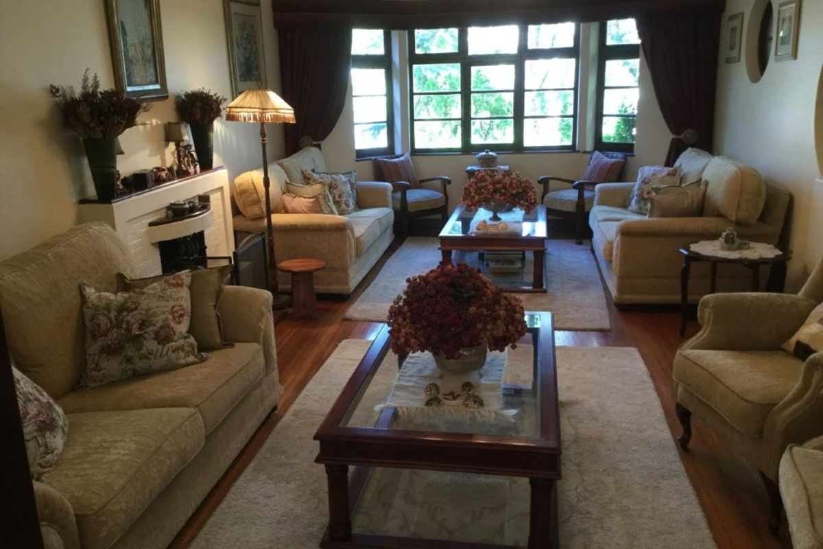 A traditional living room featuring hardwood flooring, a fireplace, and a large bay window that provides natural light.
