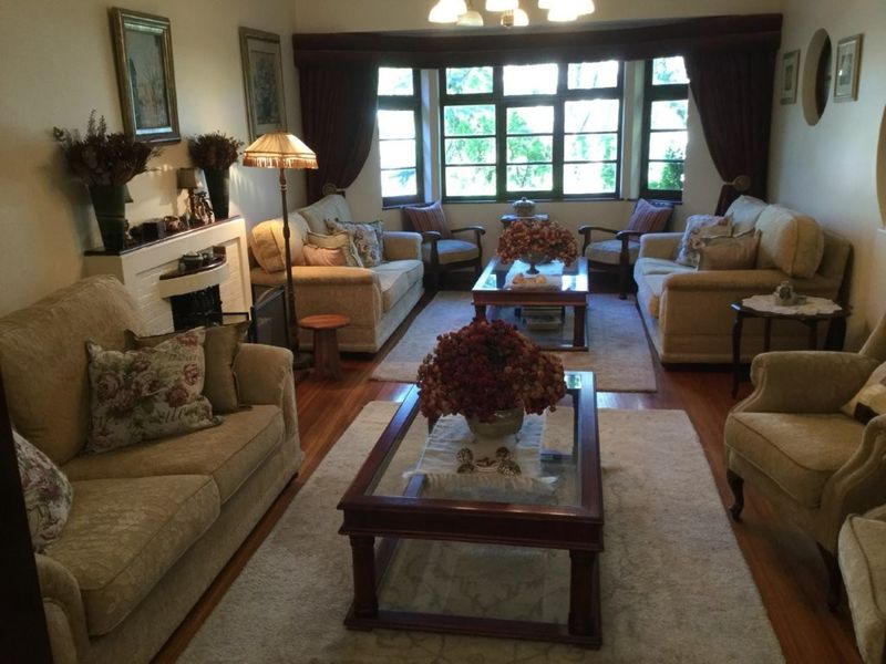 A traditional living room featuring hardwood flooring, a fireplace, and a large bay window that provides natural light.
