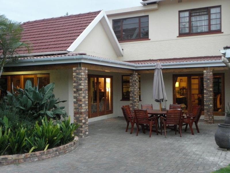 A covered patio area featuring brick pillars, paved flooring, and direct access to the interior through timber-framed doors.