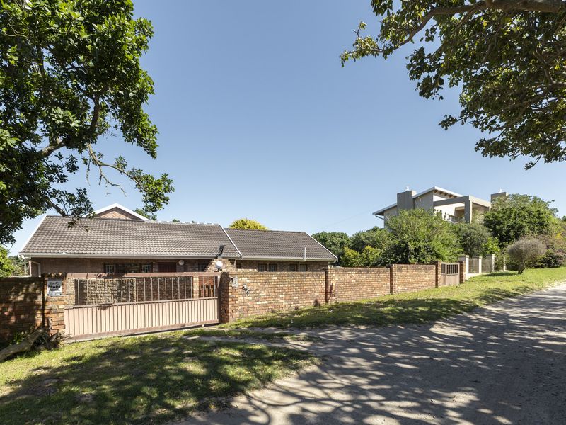 Front exterior view of the property featuring a brick boundary wall, sliding metal gate, and tiled roof structure.
