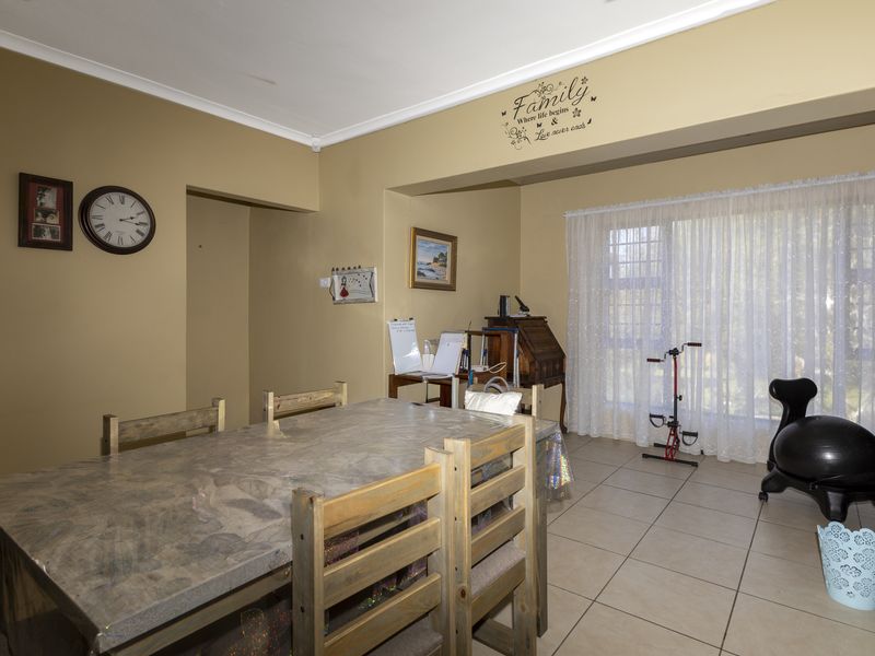 A dining room featuring tiled flooring and a sliding glass door providing natural light, with a neutral wall color and coved ceiling.