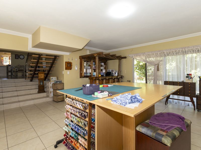 Spacious living area featuring tiled flooring, a built-in bar, and a staircase leading to an upper level, with sliding doors providing natural light.