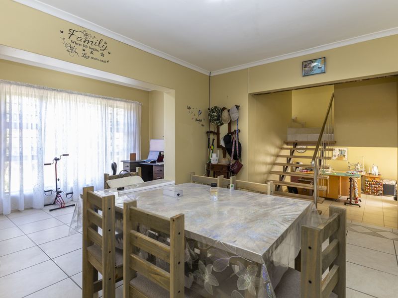 Open plan living area featuring tiled flooring and a staircase leading to an adjacent room, offering a versatile layout with natural light.