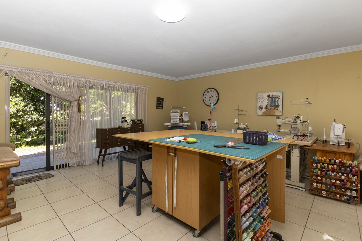 A spacious room currently utilized as a sewing studio, featuring tiled flooring and a sliding glass door providing direct access to the garden.