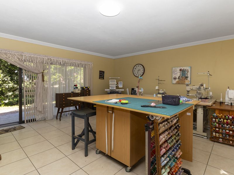 A spacious room currently utilized as a sewing studio, featuring tiled flooring and a sliding glass door providing direct access to the garden.