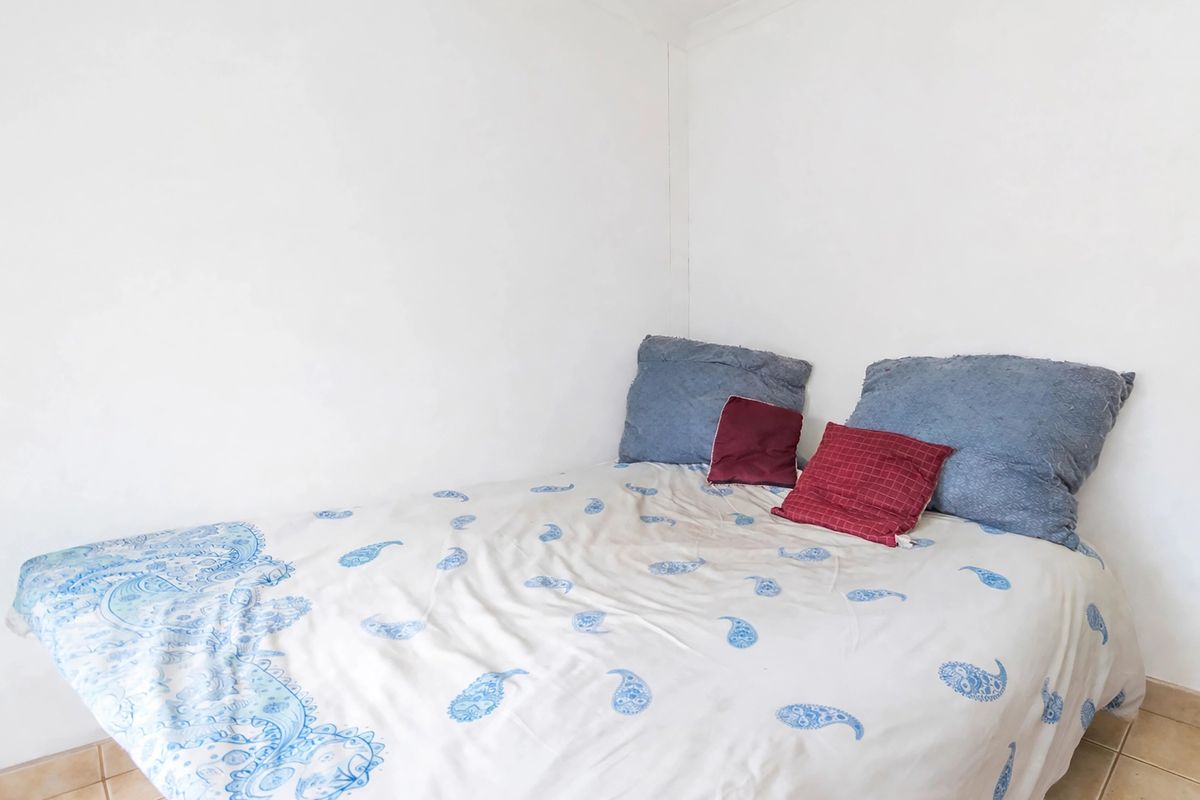 A simple bedroom featuring tiled flooring and plain white walls, providing a neutral base for potential interior design updates.