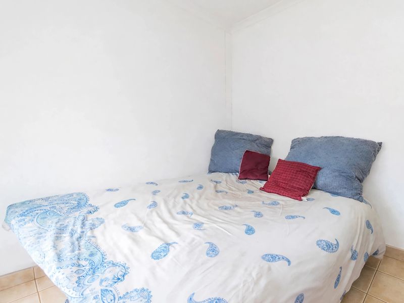 A simple bedroom featuring tiled flooring and plain white walls, providing a neutral base for potential interior design updates.