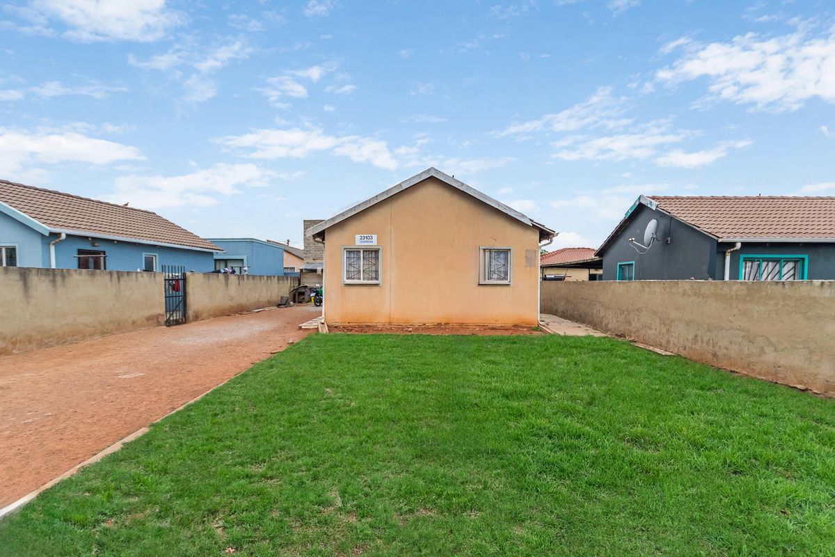 Rear view of the property featuring a private garden, perimeter boundary walls, and a secure gated entrance.