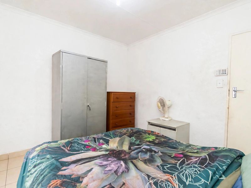 A simple bedroom featuring tiled flooring and white walls with standard cove cornicing.