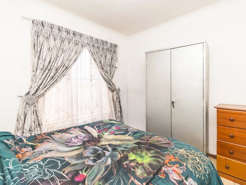 A functional bedroom featuring a built-in cupboard and a window with curtain treatments.
