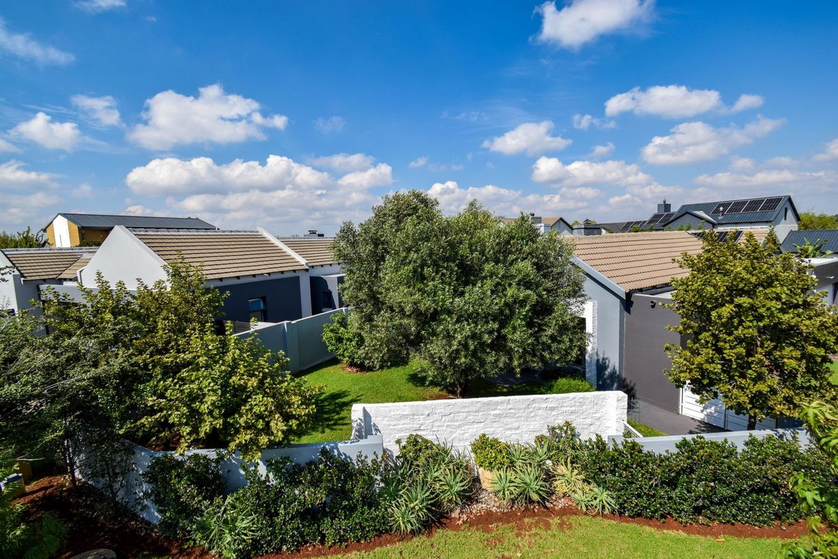An elevated view of a residential property featuring a well-maintained garden, landscaped borders, and modern house architecture with tiled roofing.