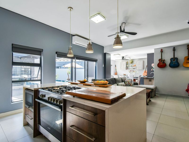 Modern open-plan kitchen featuring a central island with a built-in gas stove, sleek cabinetry, and seamless flow into the adjacent living and dining areas.