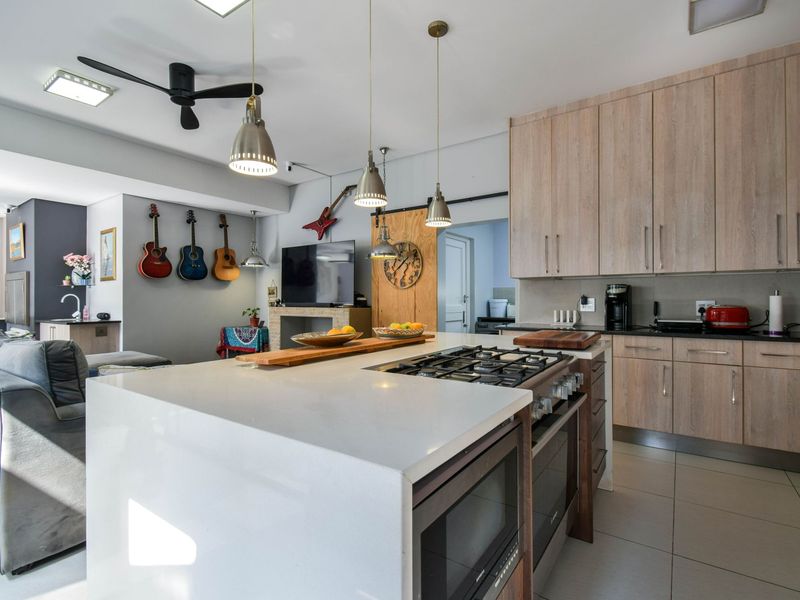 Modern open-plan kitchen and living area featuring a central island with a built-in gas hob, sleek cabinetry, and contemporary pendant lighting.