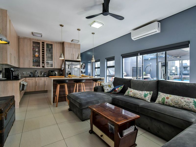 Open-plan living area featuring a modern kitchen with light wood cabinetry, breakfast bar, and direct access to the outdoor patio through sliding glass doors.