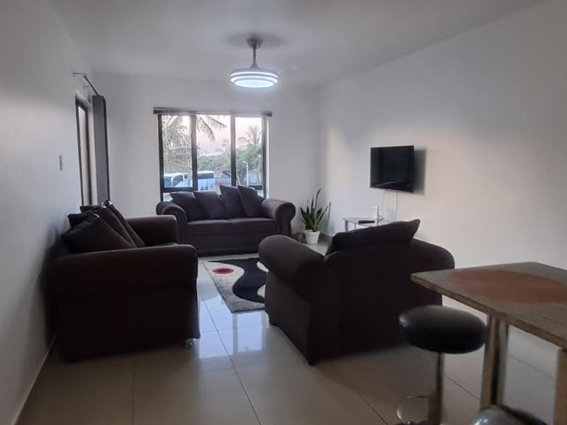 Open plan living area featuring tiled flooring, a ceiling fan, and a breakfast bar, providing a functional and connected space.