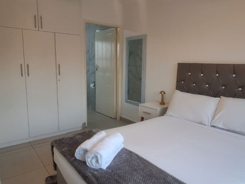A well-maintained bedroom featuring built-in cupboards, tiled flooring, and direct access to an en-suite bathroom.