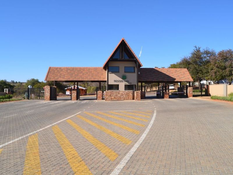 A well-maintained security gatehouse entrance featuring stone cladding, tiled roofing, and paved access lanes for a residential estate.