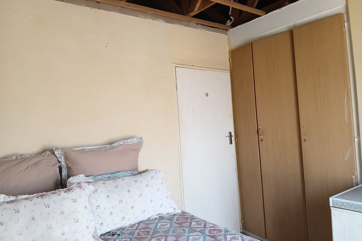 Bedroom featuring built-in cupboards, currently requiring significant ceiling repairs and wall maintenance to restore the space.