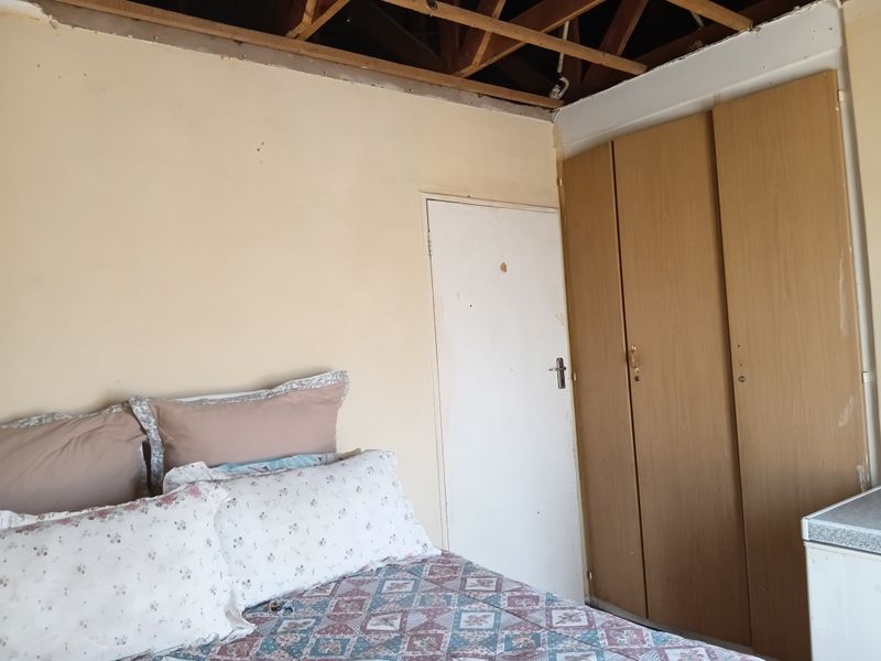Bedroom featuring built-in cupboards, currently requiring significant ceiling repairs and wall maintenance to restore the space.