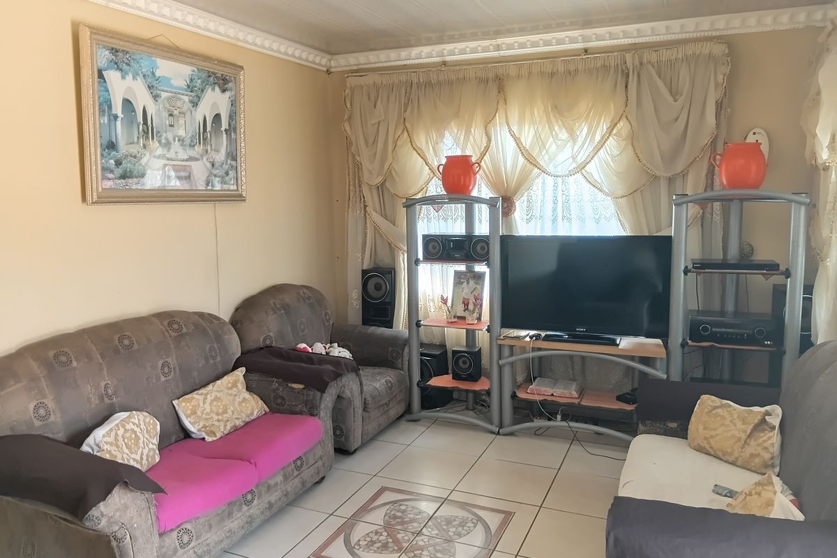 A living room featuring tiled flooring with a decorative inlay and ornate ceiling cornicing, providing a functional and traditional living space.