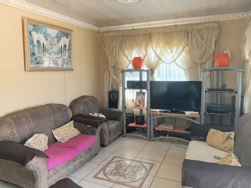 A living room featuring tiled flooring with a decorative inlay and ornate ceiling cornicing, providing a functional and traditional living space.