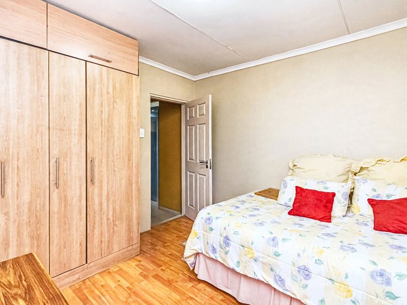 A bedroom featuring light wood-finish built-in cupboards and laminate flooring, providing functional storage and a neutral base.