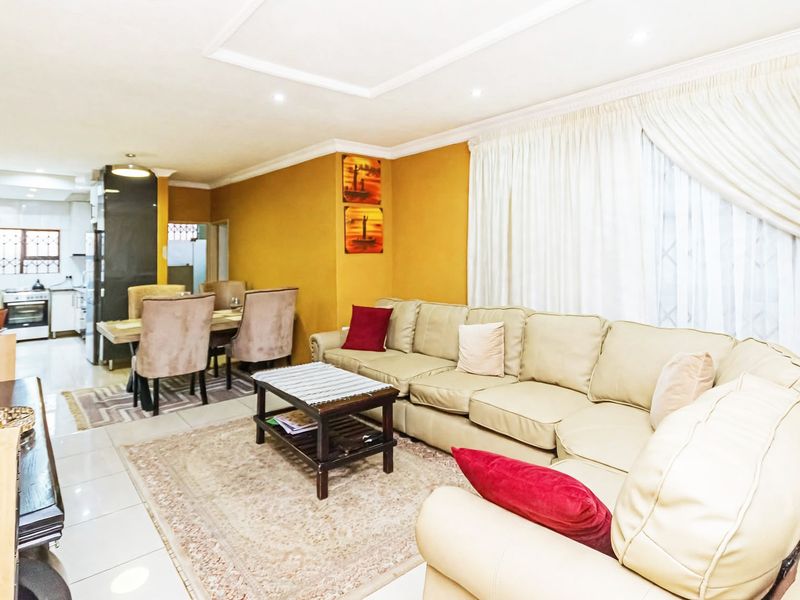 Spacious open-plan living and dining area featuring tiled floors, recessed lighting, and a functional kitchen with built-in appliances.