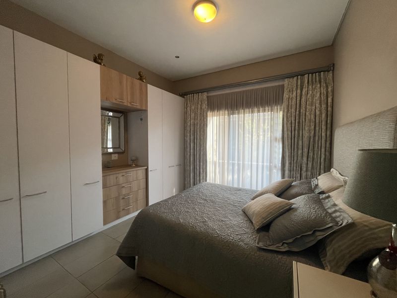 A well-maintained bedroom featuring extensive built-in cabinetry with integrated vanity, tiled flooring, and a sliding door leading to an outdoor area.