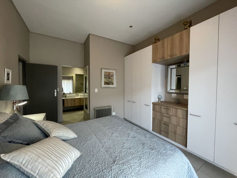 A well-maintained bedroom featuring extensive built-in cabinetry with integrated vanity and direct access to an en-suite bathroom.