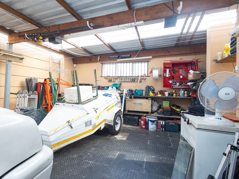 A functional garage space featuring exposed timber beams, translucent roof panels for natural light, and durable rubberized flooring.