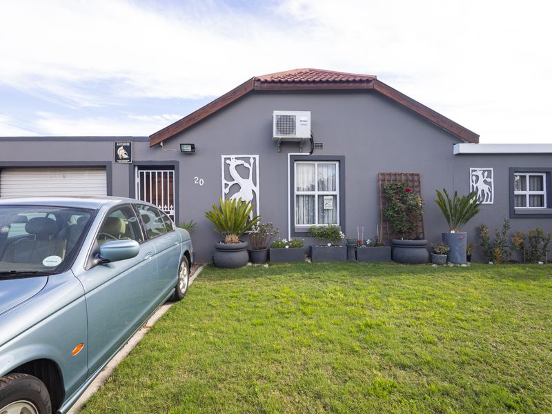Front elevation of a single-story house featuring a grey facade, tiled roof, integrated garage, and a well-maintained front lawn.